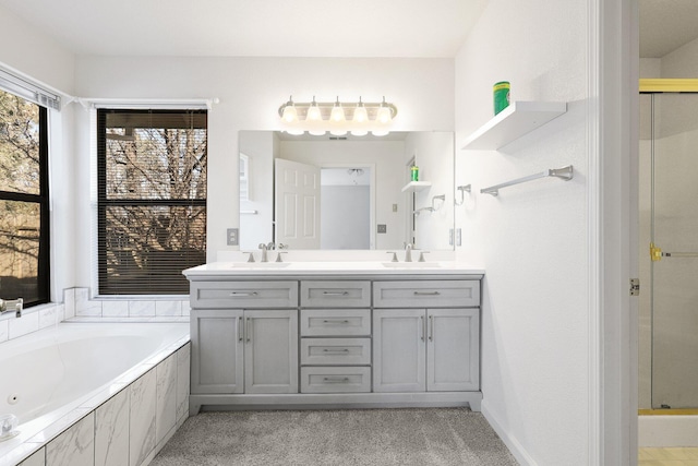 bathroom with a garden tub, double vanity, a stall shower, and a sink