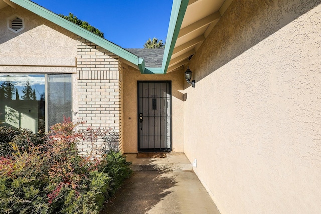 property entrance featuring brick siding and stucco siding