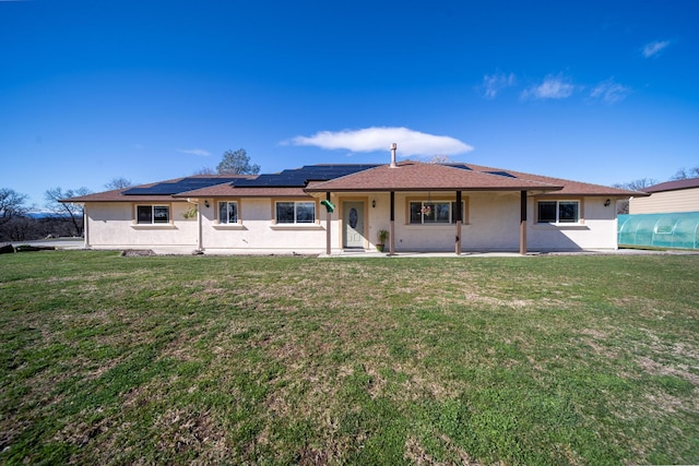 back of house with solar panels, a lawn, and stucco siding