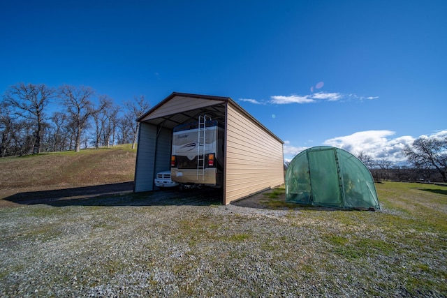 view of outdoor structure featuring a carport and an outbuilding