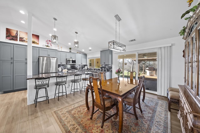 dining room featuring lofted ceiling, light wood-style floors, visible vents, and recessed lighting