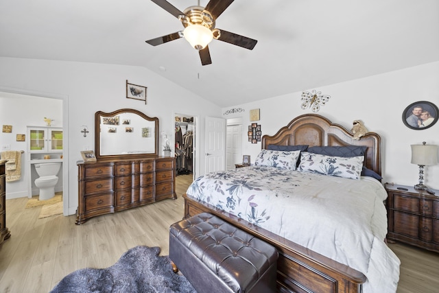 bedroom featuring light wood-type flooring, vaulted ceiling, a closet, and a walk in closet