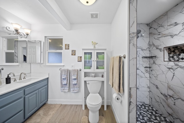 full bath featuring a marble finish shower, visible vents, vanity, wood finished floors, and baseboards