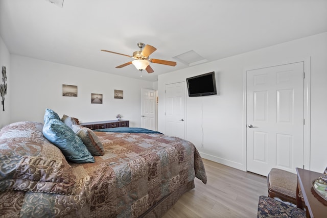 bedroom featuring ceiling fan, baseboards, light wood-style floors, a closet, and attic access