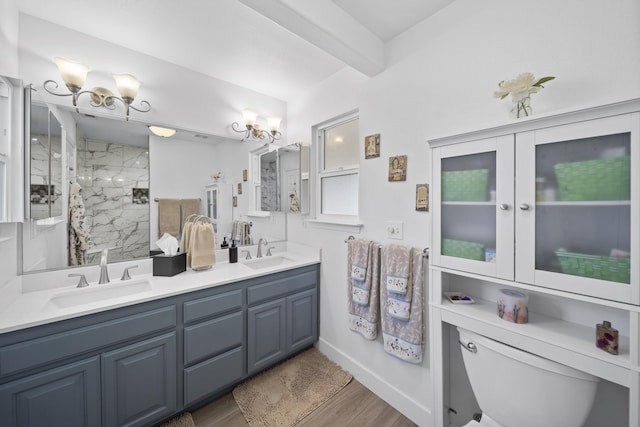 full bath with a sink, double vanity, wood finished floors, and a marble finish shower