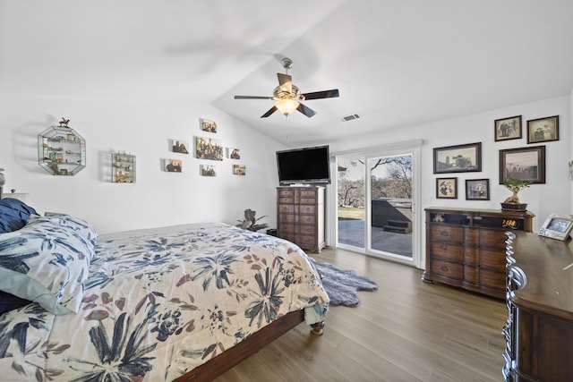 bedroom featuring visible vents, lofted ceiling, ceiling fan, wood finished floors, and access to outside