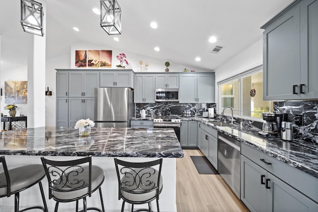 kitchen with appliances with stainless steel finishes, gray cabinets, decorative light fixtures, and a sink