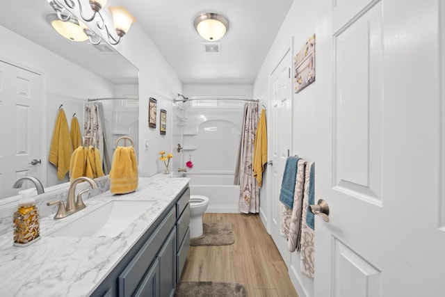 full bath with shower / tub combo, visible vents, toilet, wood finished floors, and vanity