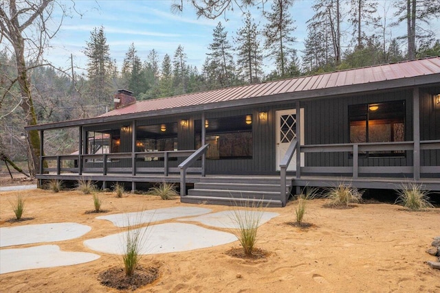 view of front of property with a chimney, covered porch, and metal roof