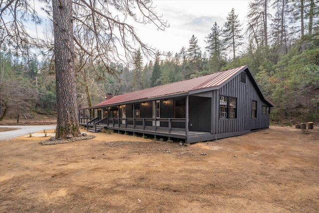 exterior space featuring a forest view, metal roof, and a porch