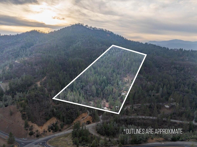 aerial view at dusk featuring a mountain view and a view of trees