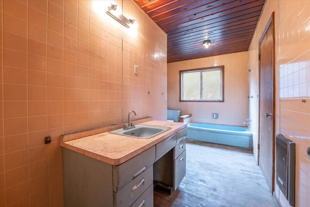 bathroom featuring heating unit, tile walls, vanity, and a bath