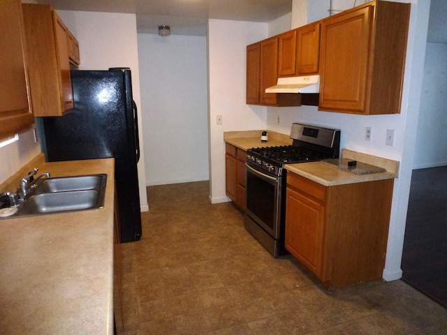 kitchen with stainless steel gas stove, sink, and black refrigerator