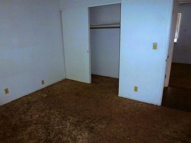 unfurnished bedroom featuring a closet and dark colored carpet