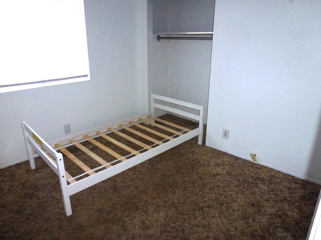 unfurnished bedroom with a closet and dark colored carpet