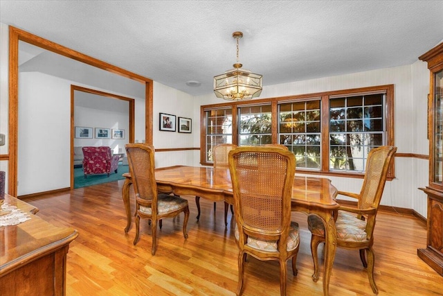 dining area with a chandelier, a textured ceiling, and light hardwood / wood-style flooring