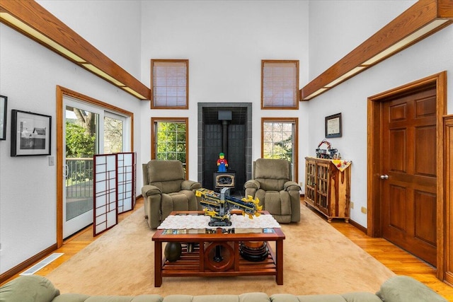 living room with a towering ceiling, light wood-type flooring, and a wood stove