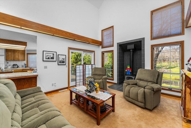 living room with a towering ceiling, a wood stove, and light wood-type flooring