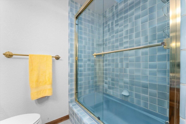 bathroom featuring toilet and combined bath / shower with glass door