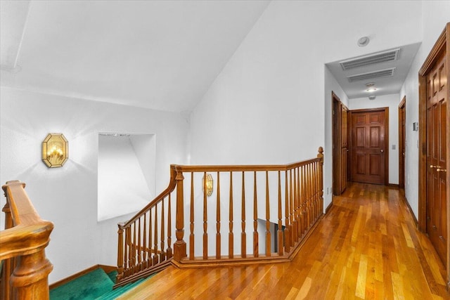 hallway with vaulted ceiling and hardwood / wood-style floors