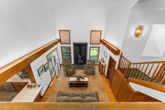 living room featuring light hardwood / wood-style floors, a wood stove, and a high ceiling