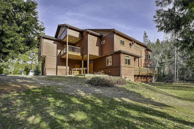 rear view of house featuring a yard and a balcony