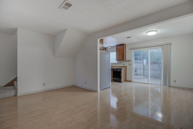 unfurnished living room featuring a textured ceiling and light hardwood / wood-style flooring