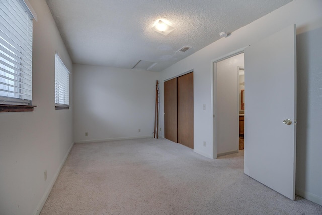 unfurnished bedroom with light carpet, a closet, and a textured ceiling