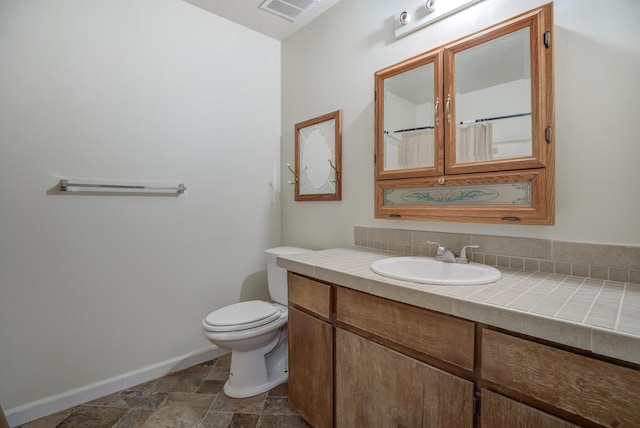 bathroom featuring walk in shower, vanity, and toilet