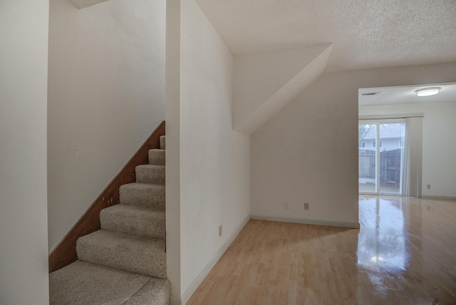 staircase with wood-type flooring and a textured ceiling