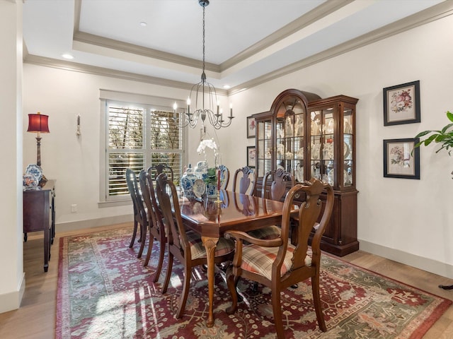 dining room featuring crown molding, a notable chandelier, light wood-type flooring, and a tray ceiling