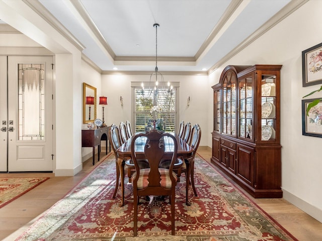 dining space featuring a chandelier, crown molding, a raised ceiling, and light hardwood / wood-style floors