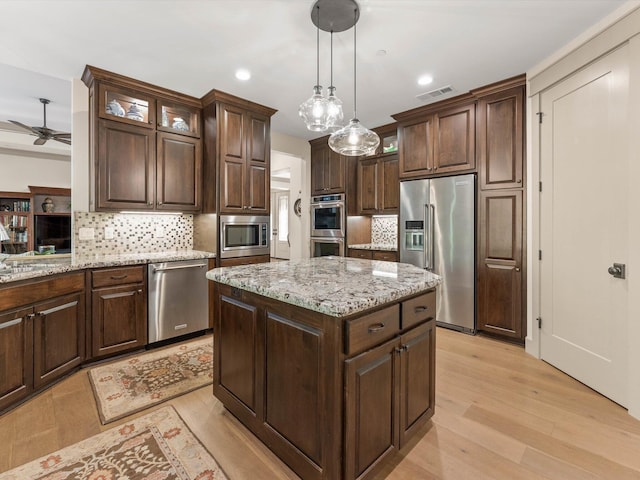 kitchen with dark brown cabinetry, stainless steel appliances, decorative light fixtures, and a kitchen island