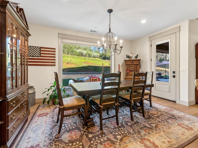 dining area with light wood-type flooring and a notable chandelier