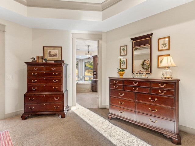 carpeted bedroom with a raised ceiling, connected bathroom, and a chandelier