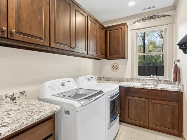 clothes washing area with light tile patterned flooring, cabinets, separate washer and dryer, and sink