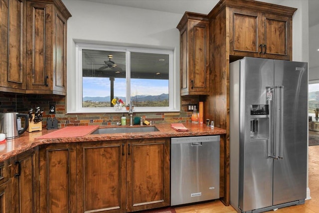 kitchen featuring sink, tasteful backsplash, light stone counters, appliances with stainless steel finishes, and ceiling fan