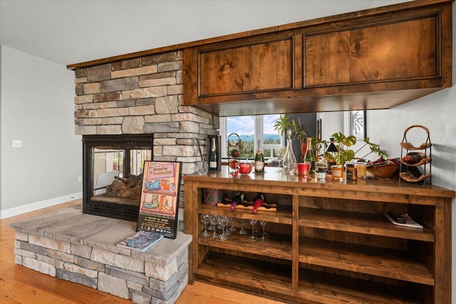 bar with light hardwood / wood-style flooring and a fireplace