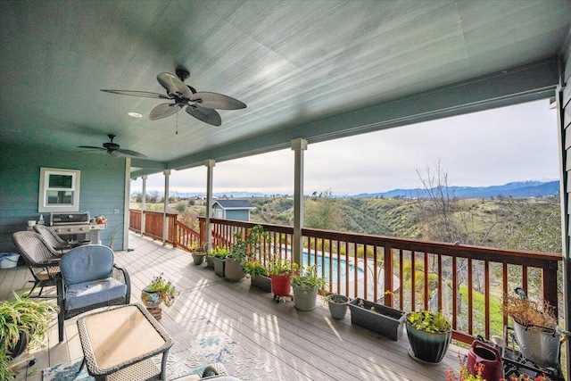 deck featuring a fenced in pool, a mountain view, area for grilling, and ceiling fan