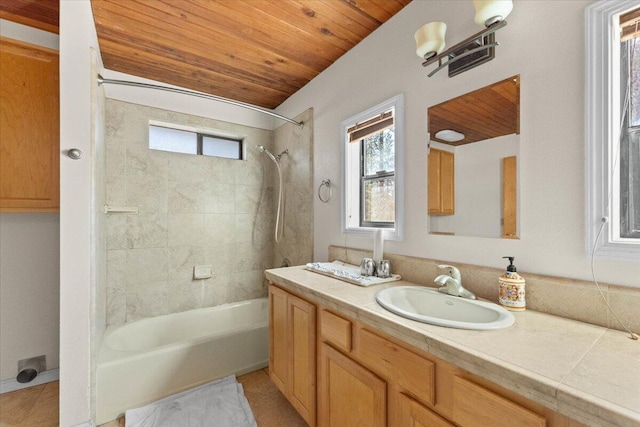 bathroom featuring tiled shower / bath, wooden ceiling, and vanity