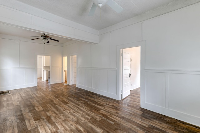 unfurnished room with dark wood finished floors, visible vents, a decorative wall, ceiling fan, and a textured ceiling