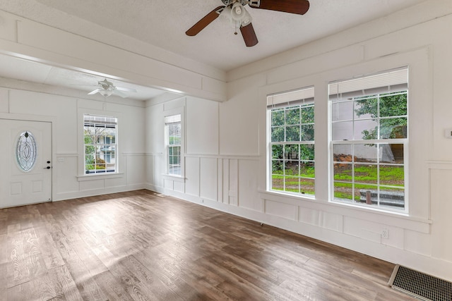 empty room featuring a textured ceiling, visible vents, a decorative wall, and wood finished floors