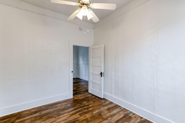 spare room with ceiling fan, dark wood-style flooring, and baseboards