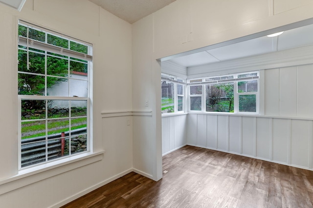 unfurnished room featuring a wealth of natural light, baseboards, and wood finished floors