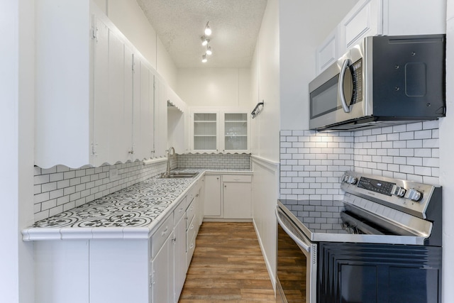 kitchen with stainless steel appliances, light countertops, white cabinetry, and a sink