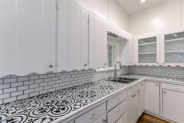 kitchen featuring white cabinets, light countertops, a sink, and decorative backsplash