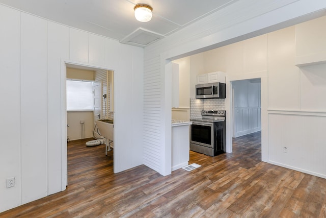 kitchen with stainless steel appliances, light countertops, white cabinets, and dark wood-type flooring