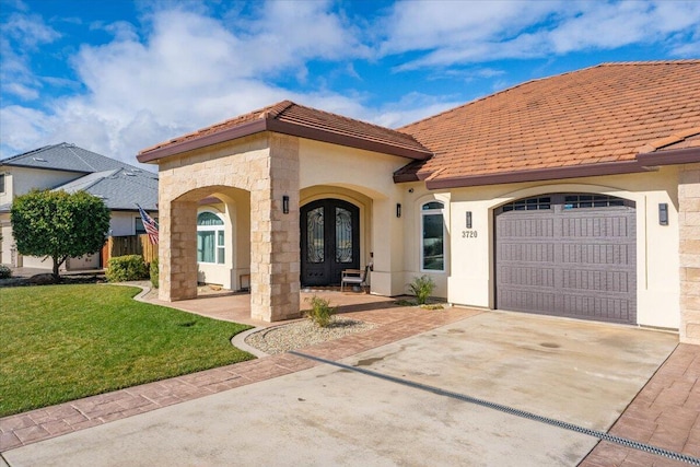 mediterranean / spanish house with a garage, a front yard, and french doors