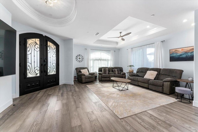 living room featuring a healthy amount of sunlight, a tray ceiling, and light wood-type flooring