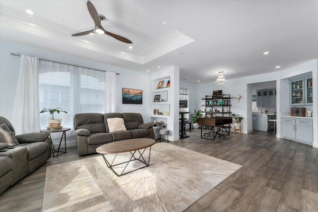 living room featuring ceiling fan, ornamental molding, dark hardwood / wood-style floors, and a raised ceiling